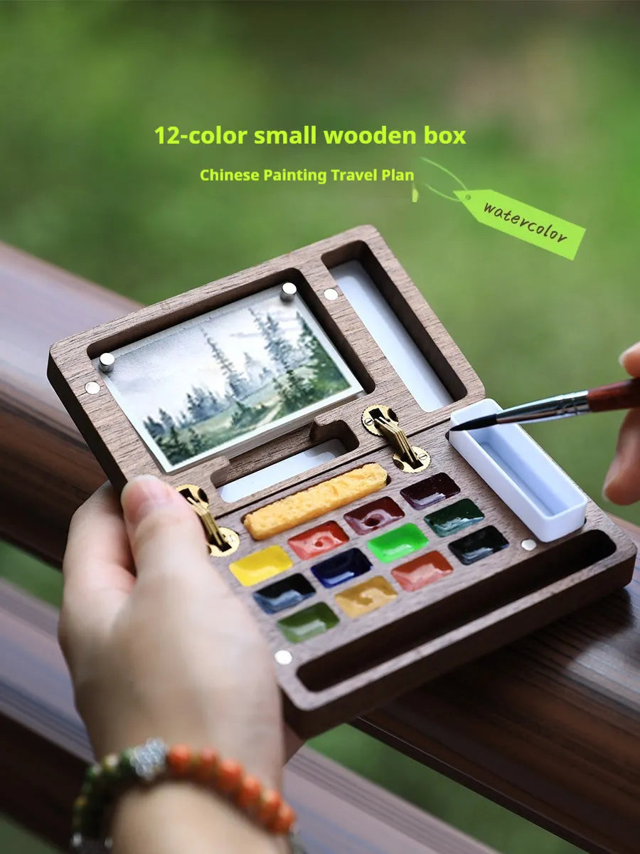 Mini wooden watercolour paint box open to show pigment pans inside.
