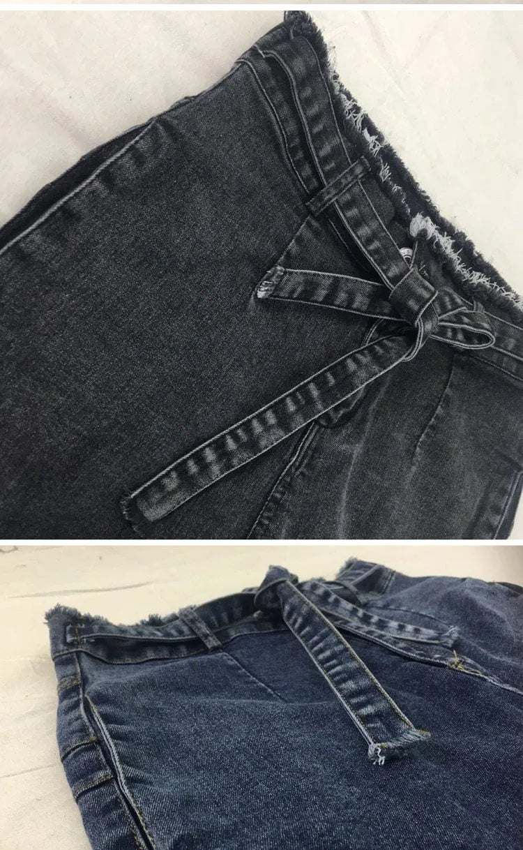 A pair of distressed grey fringed jeans made from Cowboy denim fabric on a neutral background.