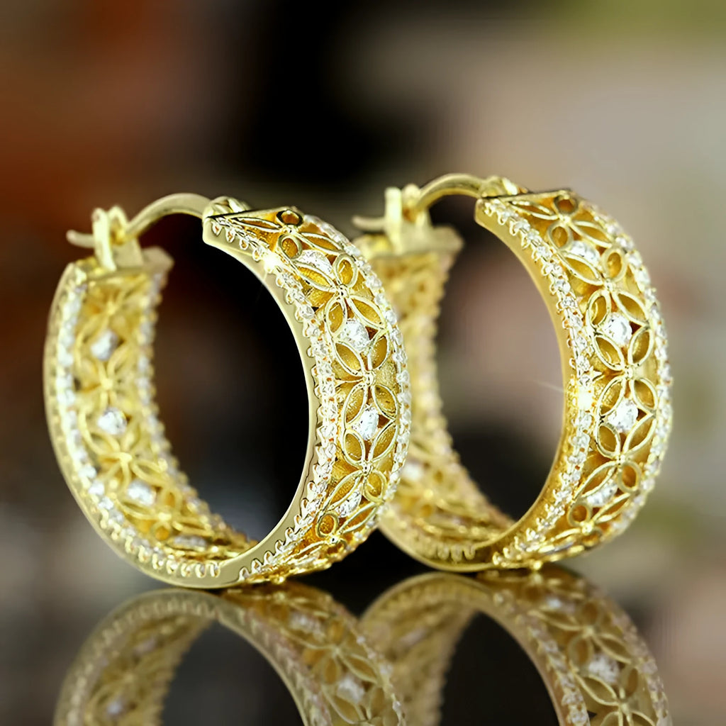 A pair of geometric copper ear clips with horse eye, flower and butterfly motifs in a yellow gold colour.