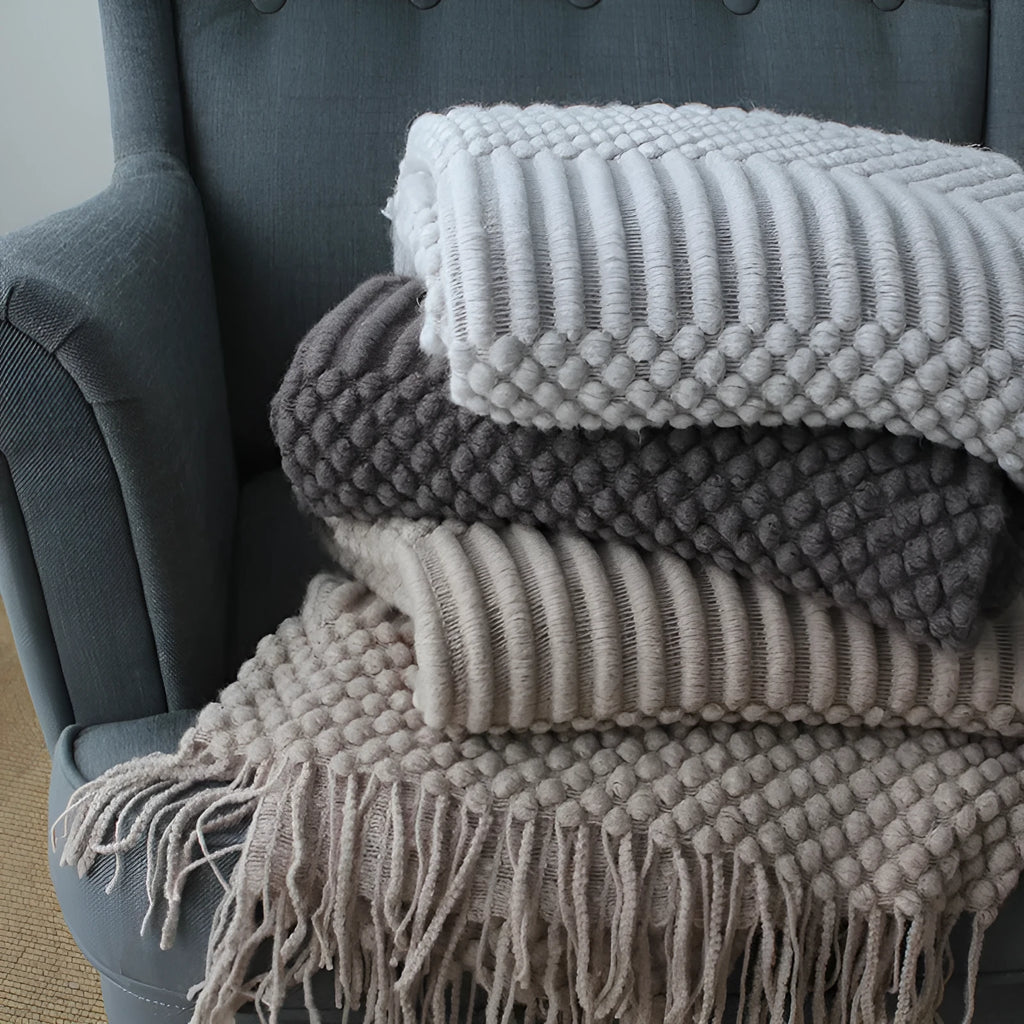 Small light grey polyester nap blanket folded on a sofa, showing its size.