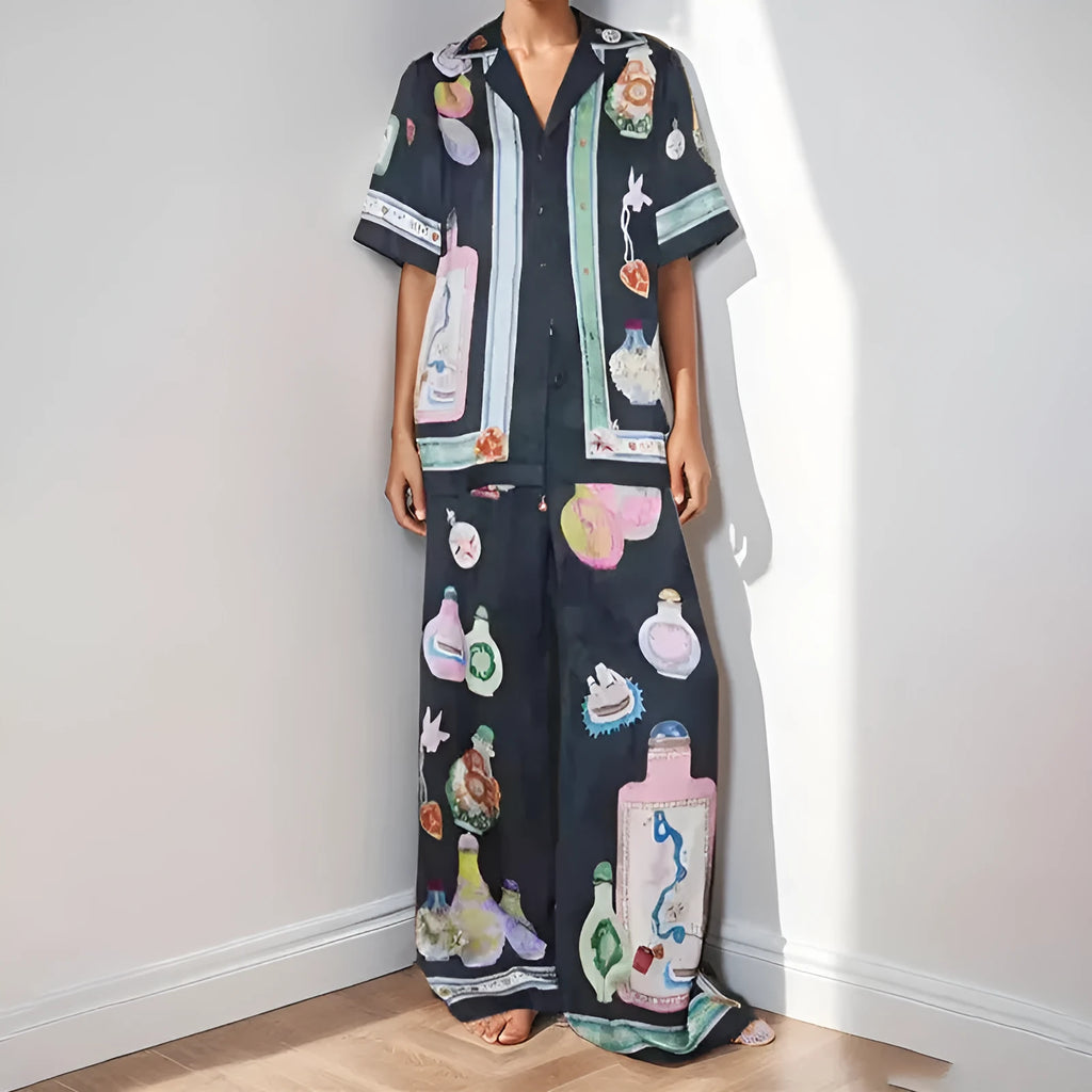 Black women's cardigan and pants set with cartoon animation pattern, shown laid flat.