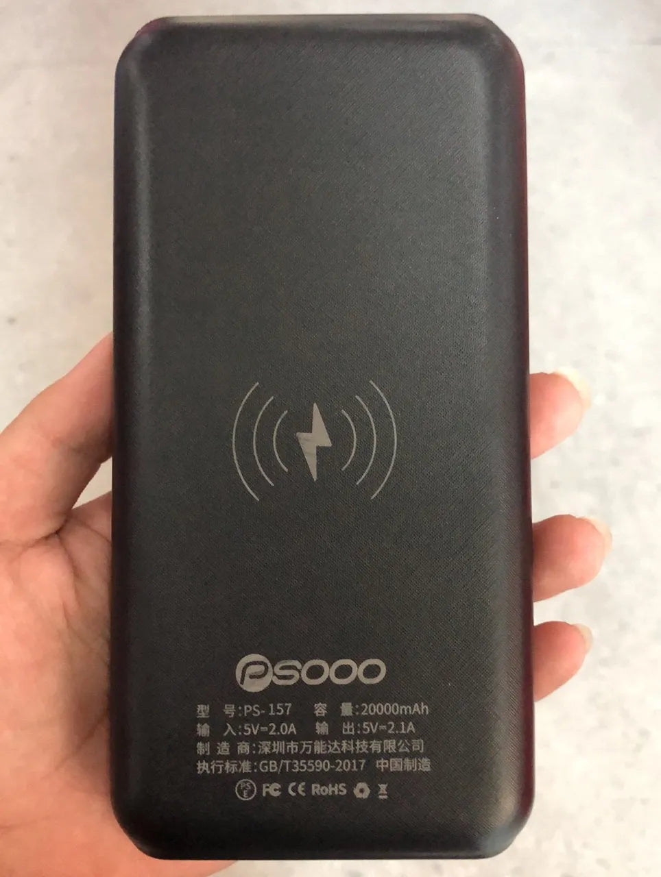Black portable power bank with wireless Qi charging pad, three USB ports, and LED flashlight