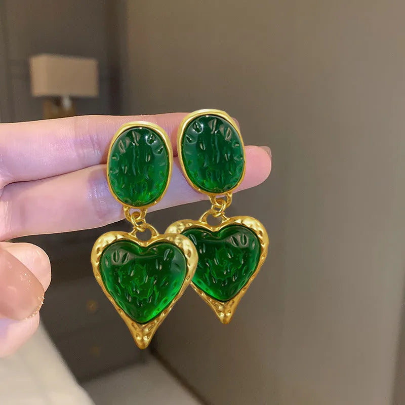 Four pairs of oval love heart stud earrings with silver needle pleated detailing in purple, red, green, and yellow-white colours