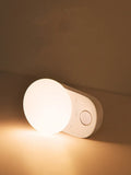 White Baseus rechargeable night light with motion sensor on a bedside table.