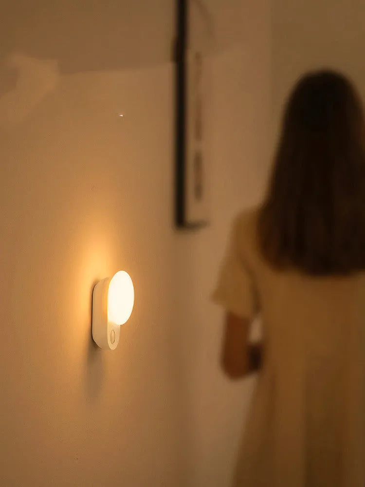 White Baseus rechargeable night light with motion sensor on a bedside table.