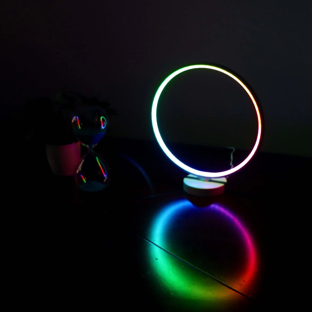White full moon shaped table lamp with soft glow, placed on a surface with remote control.