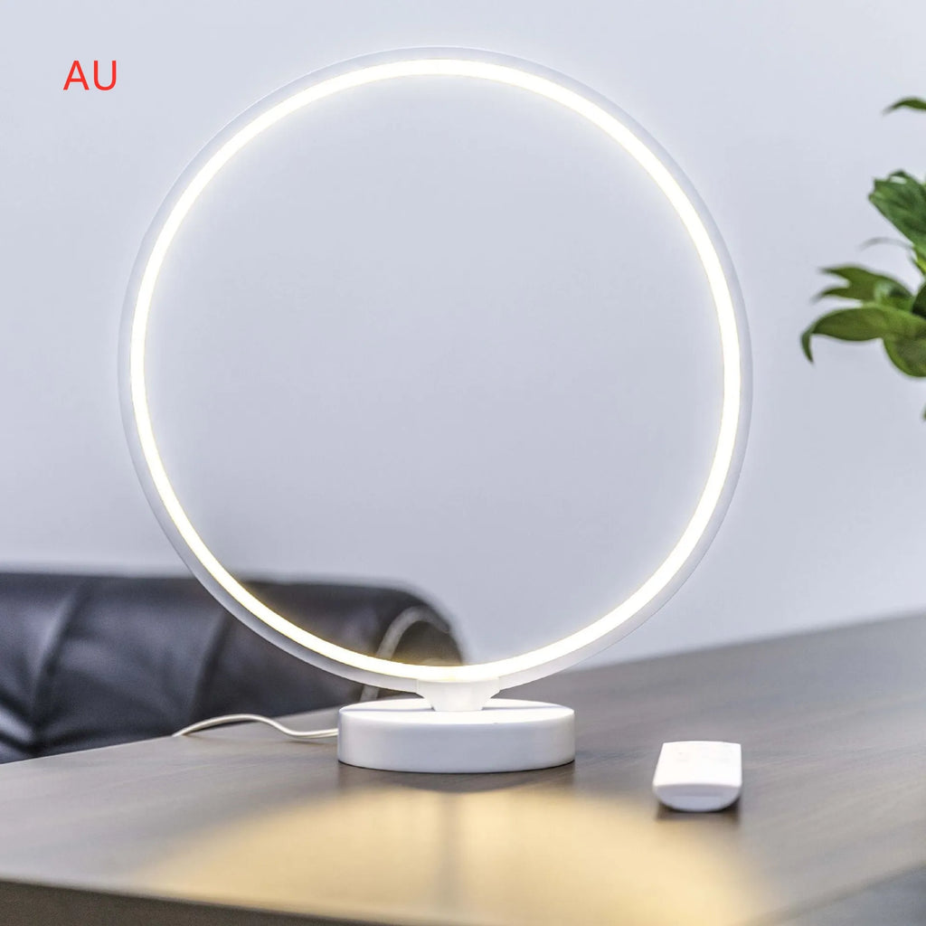 White full moon shaped table lamp with soft glow, placed on a surface with remote control.