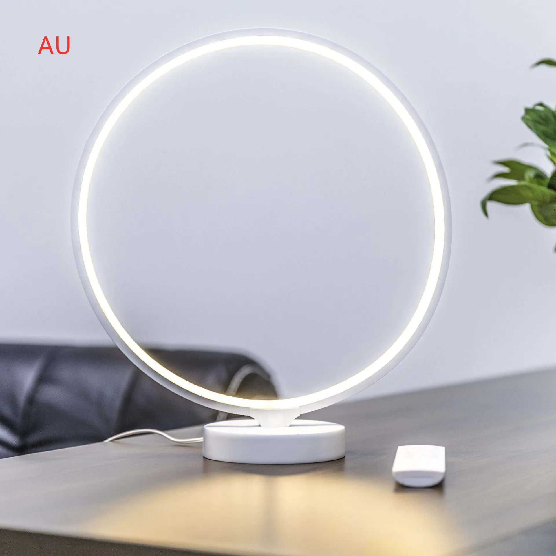 White full moon shaped table lamp with soft glow, placed on a surface with remote control.