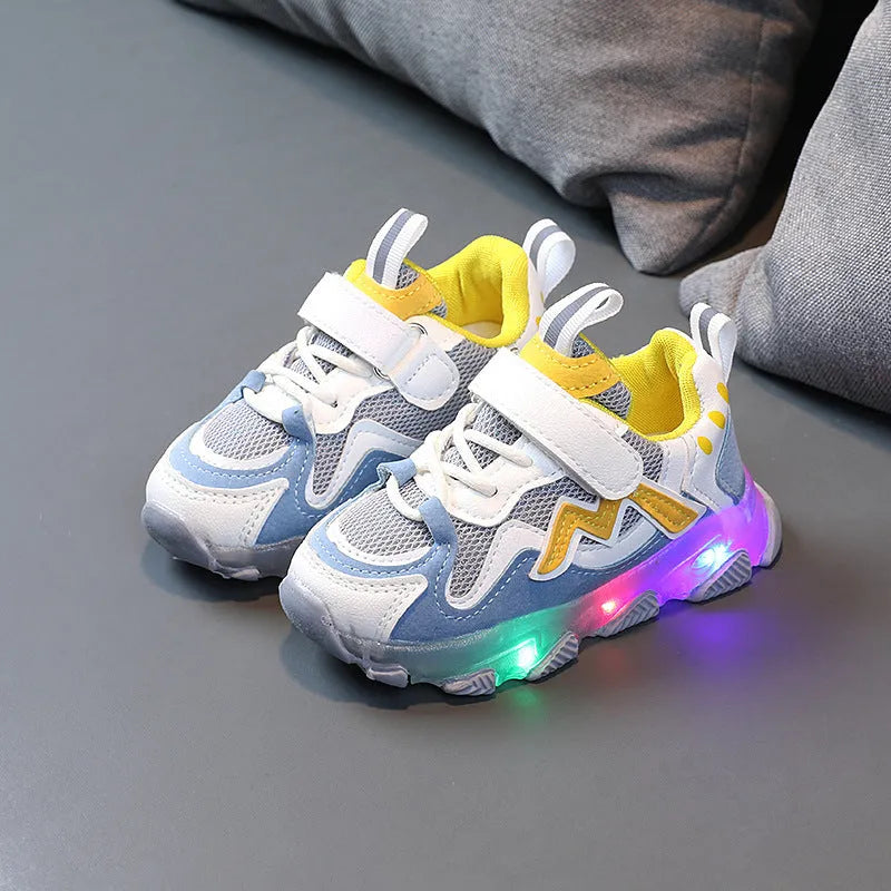 Kids' black mesh sneakers with Velcro strap and light grey rubber sole on a paved surface.