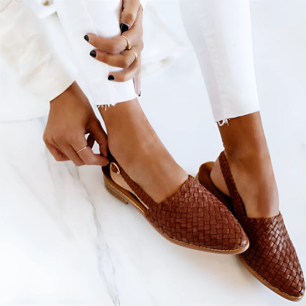 Women's black flat sandals with a silver buckle and pointed toe on a rubber sole.