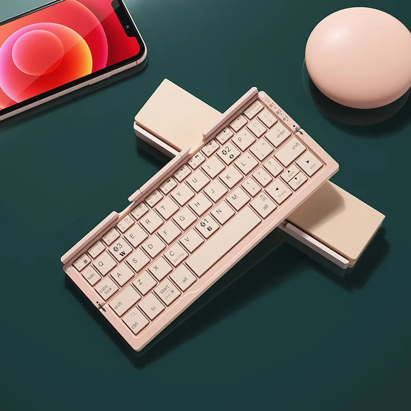 Silver folding Bluetooth keyboard open with tablet on stand, showing compact size and 60-key layout