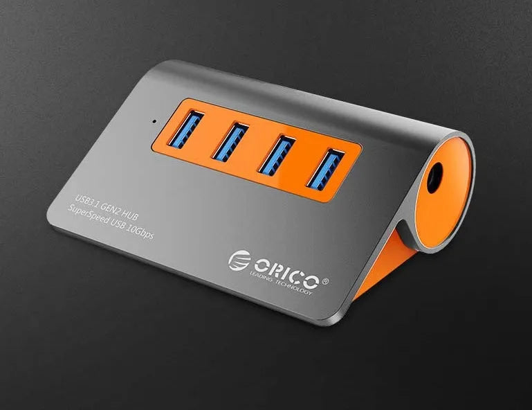 Dark grey aluminium USB hub with orange accents and separate cable showing four USB 3.1 ports