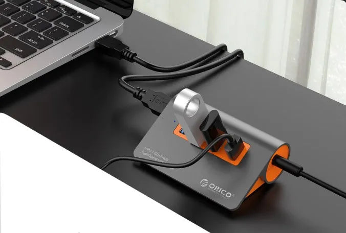 Dark grey aluminium USB hub with orange accents and separate cable showing four USB 3.1 ports