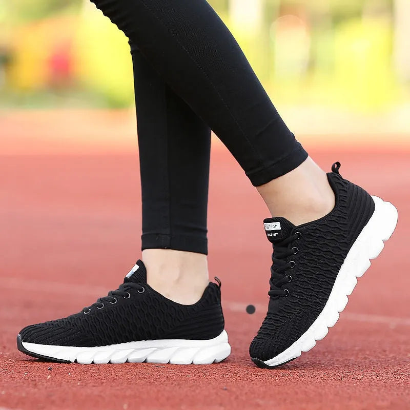 Women's running shoes in black, pink, and white with fly weaving upper and wear-resistant outsole