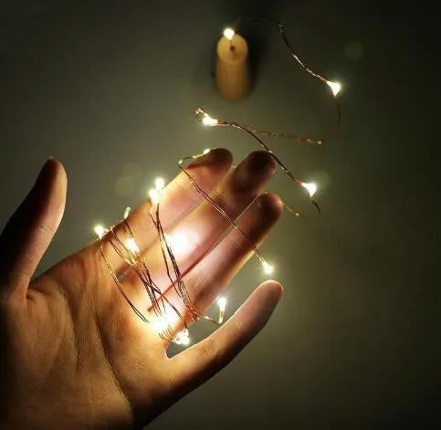 Flexible copper wire LED string lights wrapped around wine bottle with warm white illumination
