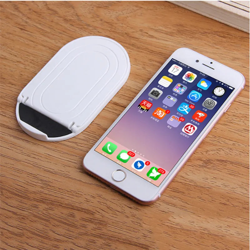 A plastic lazy bracket mobile phone stand holding a smartphone, shown in multiple colour options.
