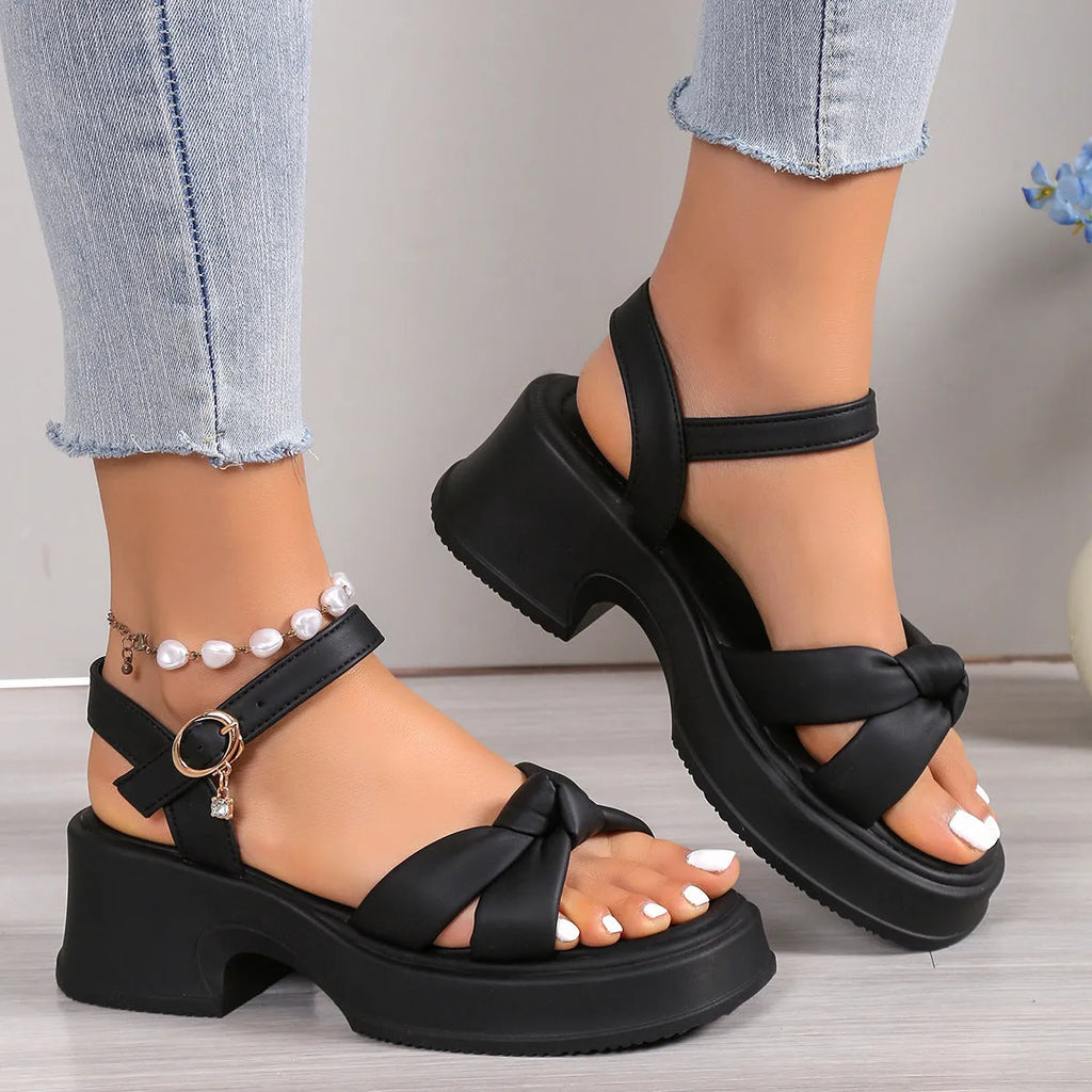 Black wedge heel slippers with round toe and a single button fastening on the strap.