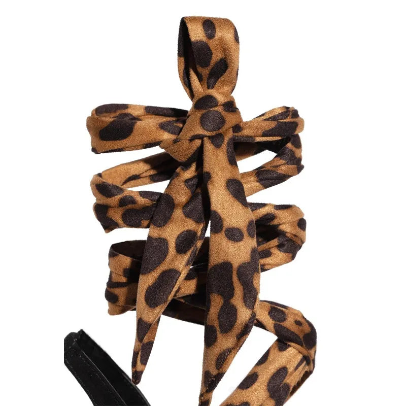 Light brown leopard print women's high-heel sandals with cross straps and a thin stiletto heel.