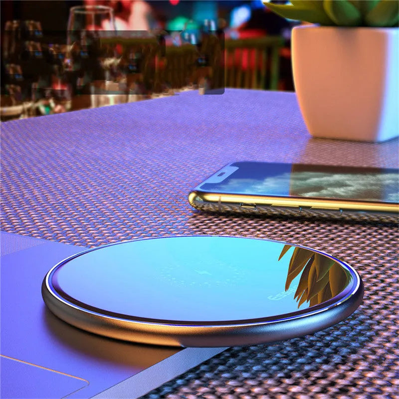 Black 15W Qi fast wireless charging pad with aluminium body and LED light, shown next to a smartphone.