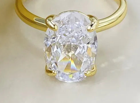 Women's oval 9K silver ring with a four-prong setting, shown in gold and silver tone finishes.