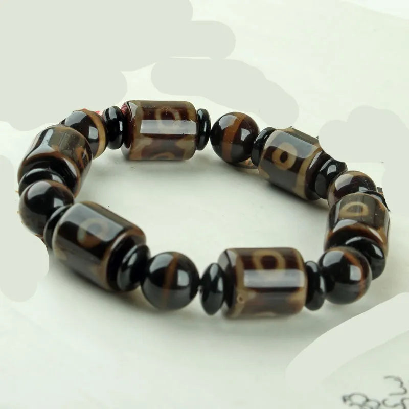 Distressed agate Tibetan bead bracelet with three-eye motifs and polished finish.