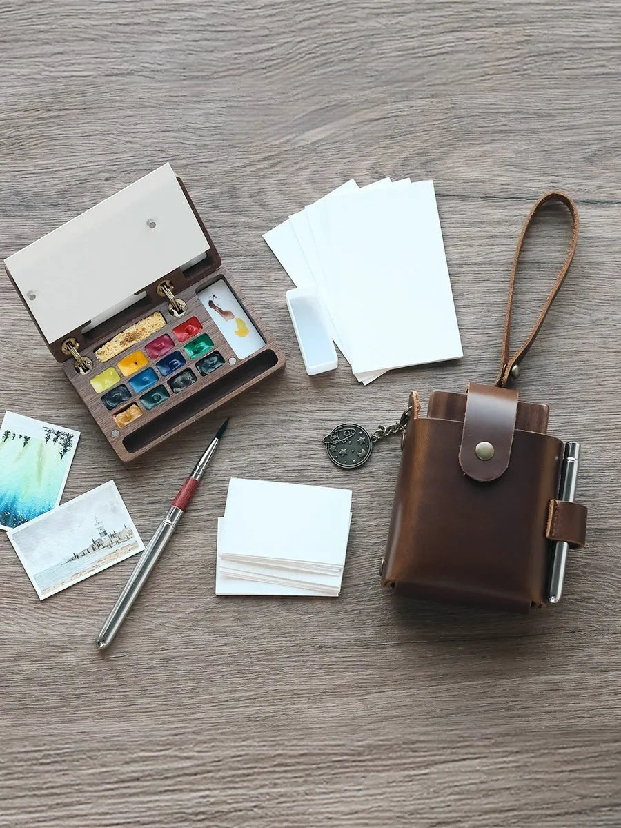 Mini wooden watercolour paint box open to show pigment pans inside.