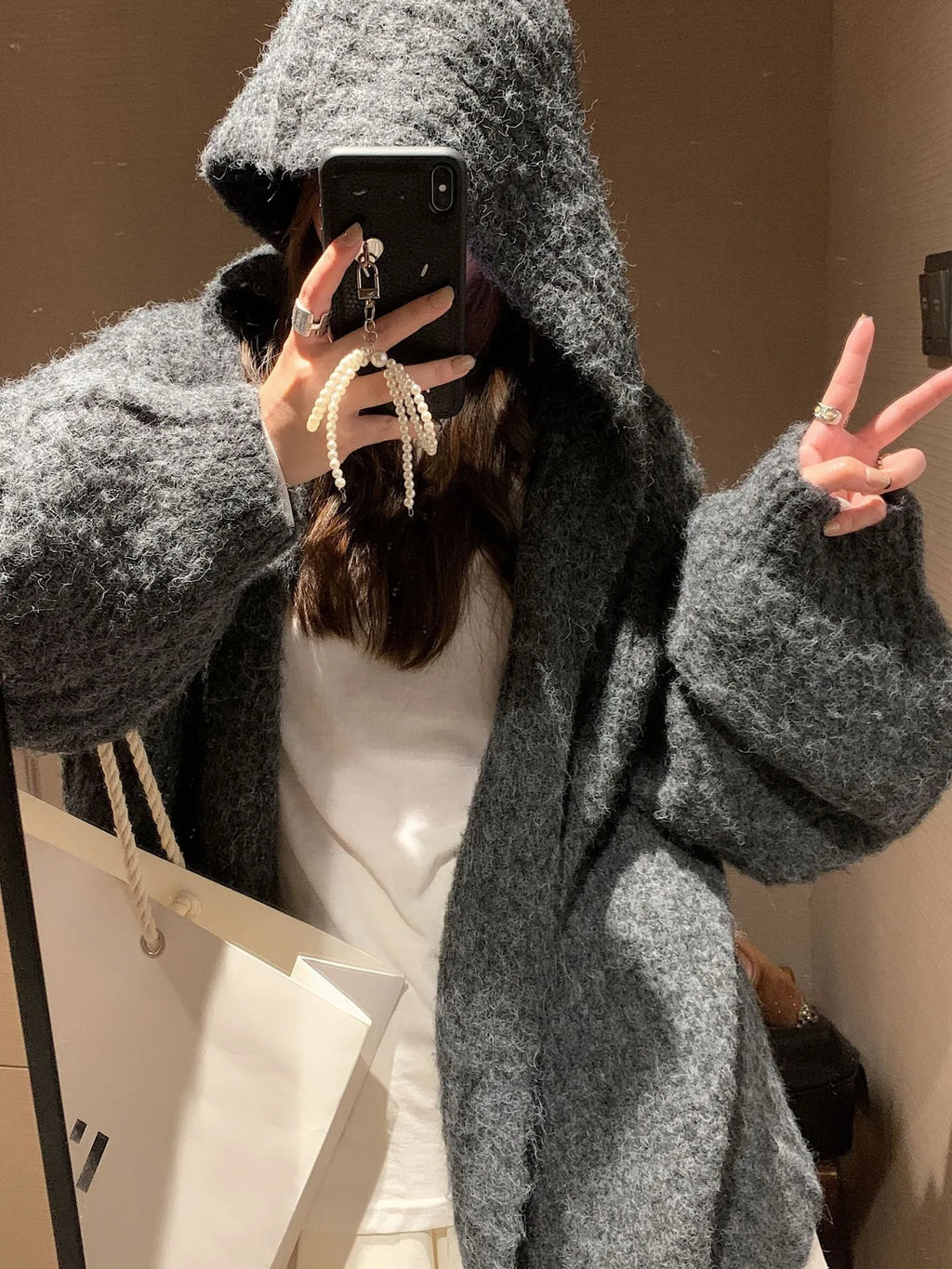 A woman's loose-fit hooded sweater cardigan in a thick fabric, shown in dark grey, brown, and milky white colour options.