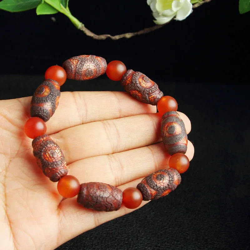 Distressed agate Tibetan bead bracelet with three-eye motifs and polished finish.