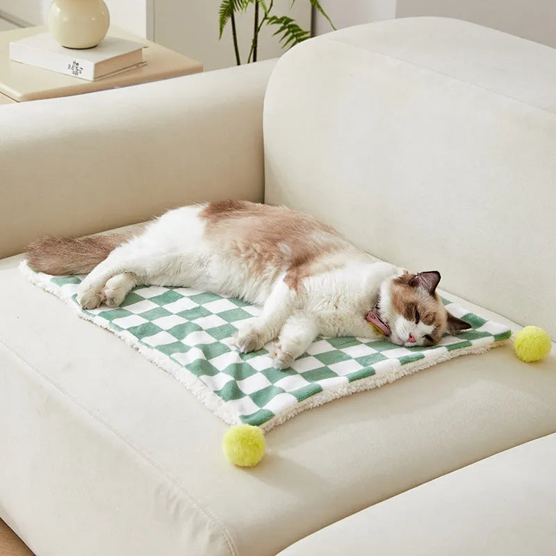 Plush pet blanket with bright plaid pattern and fur ball decorations for cats and dogs