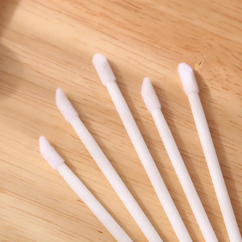 Pack of disposable flocked lip brush applicators with coloured handles on a white surface.