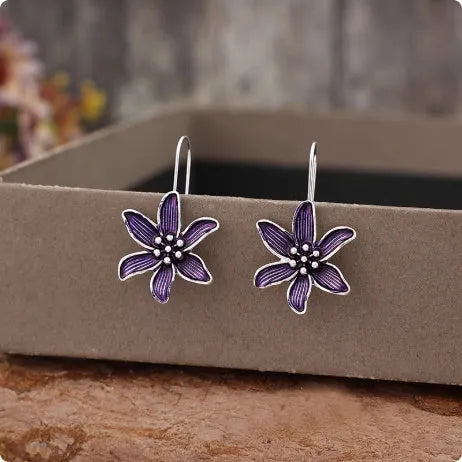 A pair of simple purple flower-shaped alloy earrings for women on a white background.