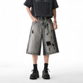 Grey women's denim shorts with a water washed finish, distressed holes, and a loose cropped fit.