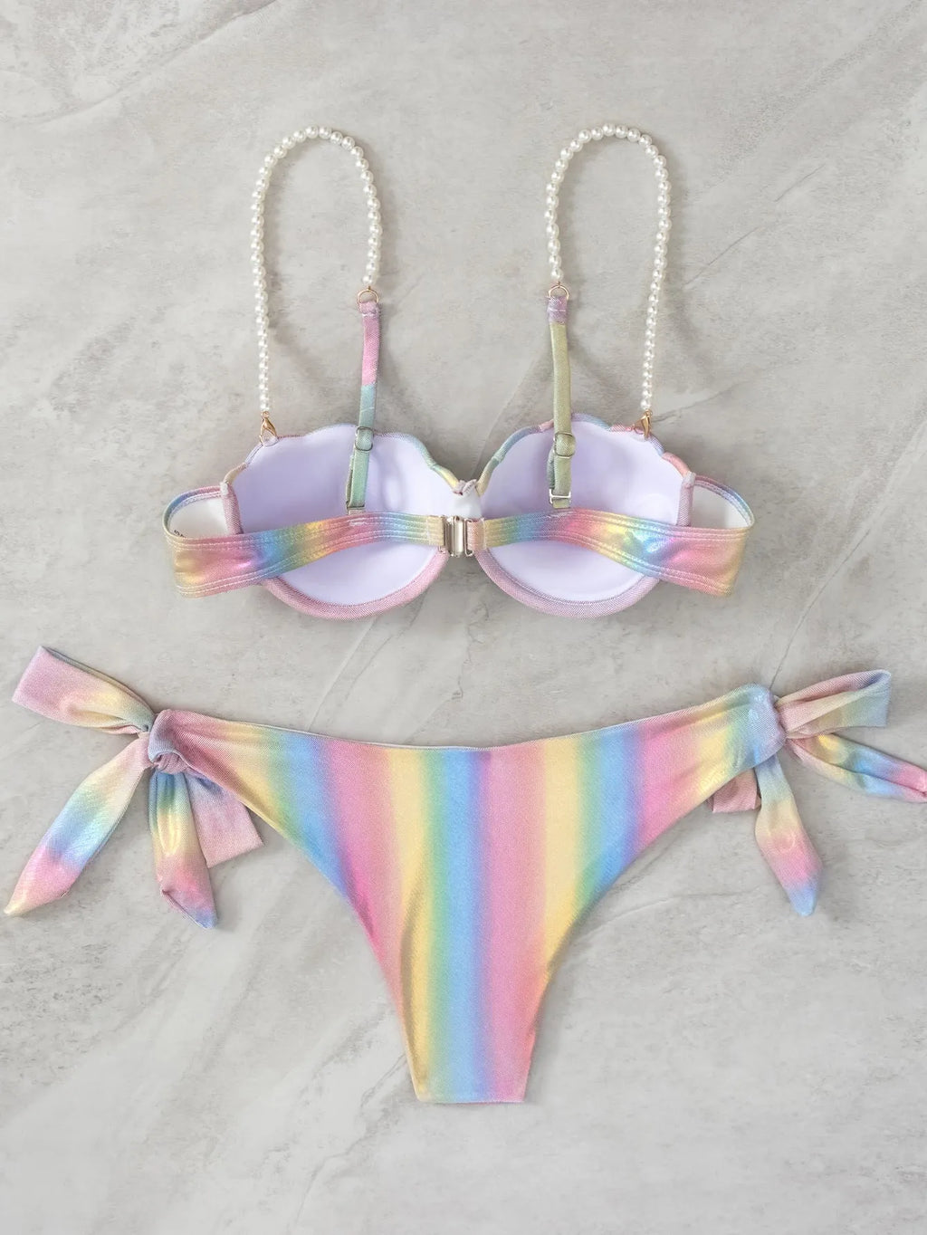 Women's rainbow tie dye bikini swimsuit with split tied sides on a model.