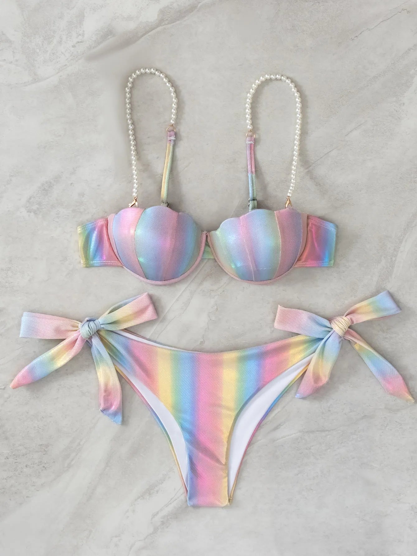 Women's rainbow tie dye bikini swimsuit with split tied sides on a model.