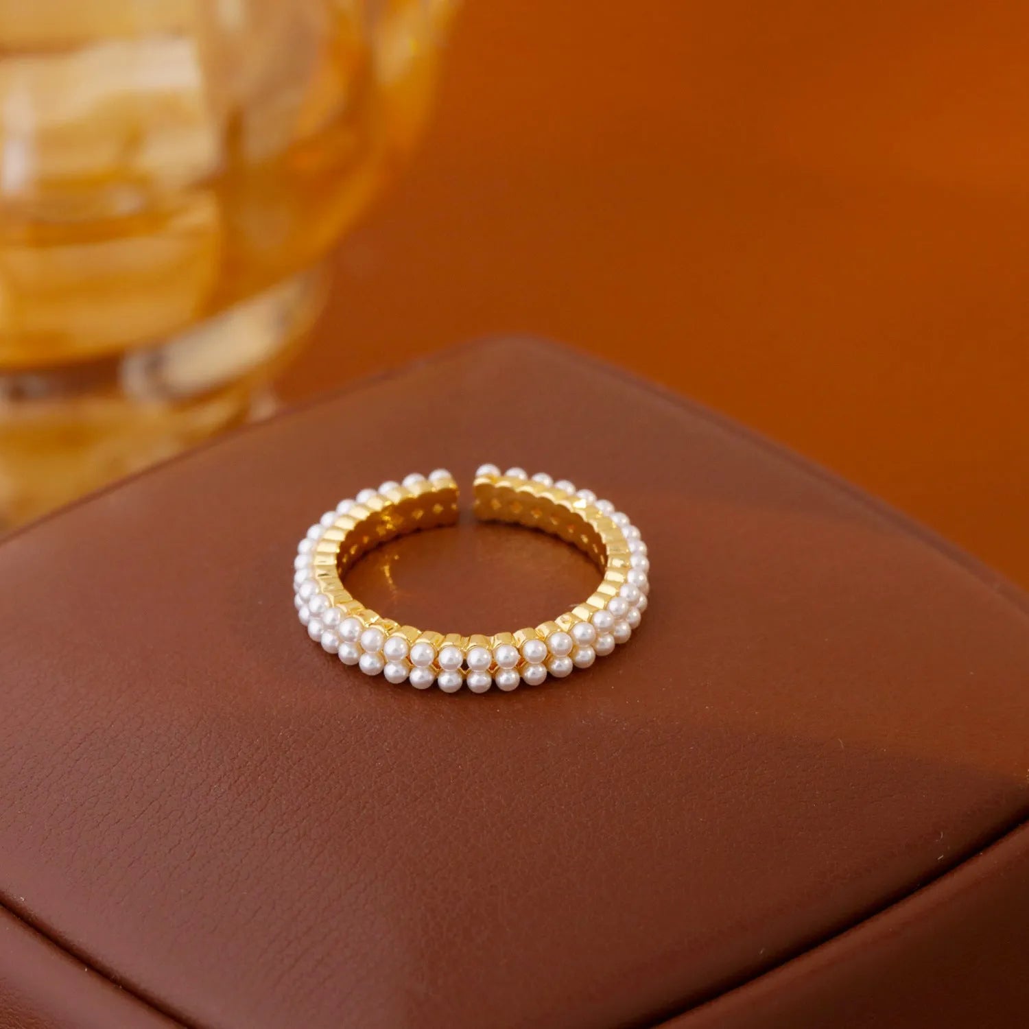 Gold geometric ring with open mouth design and pearl elements on female hand