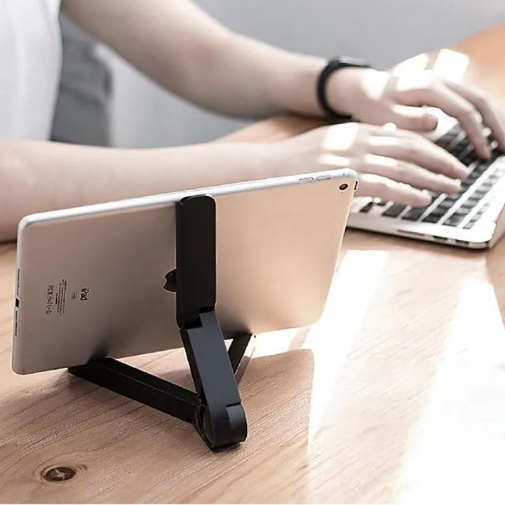 Black foldable aluminium tablet holder shown open and folded flat next to a smartphone