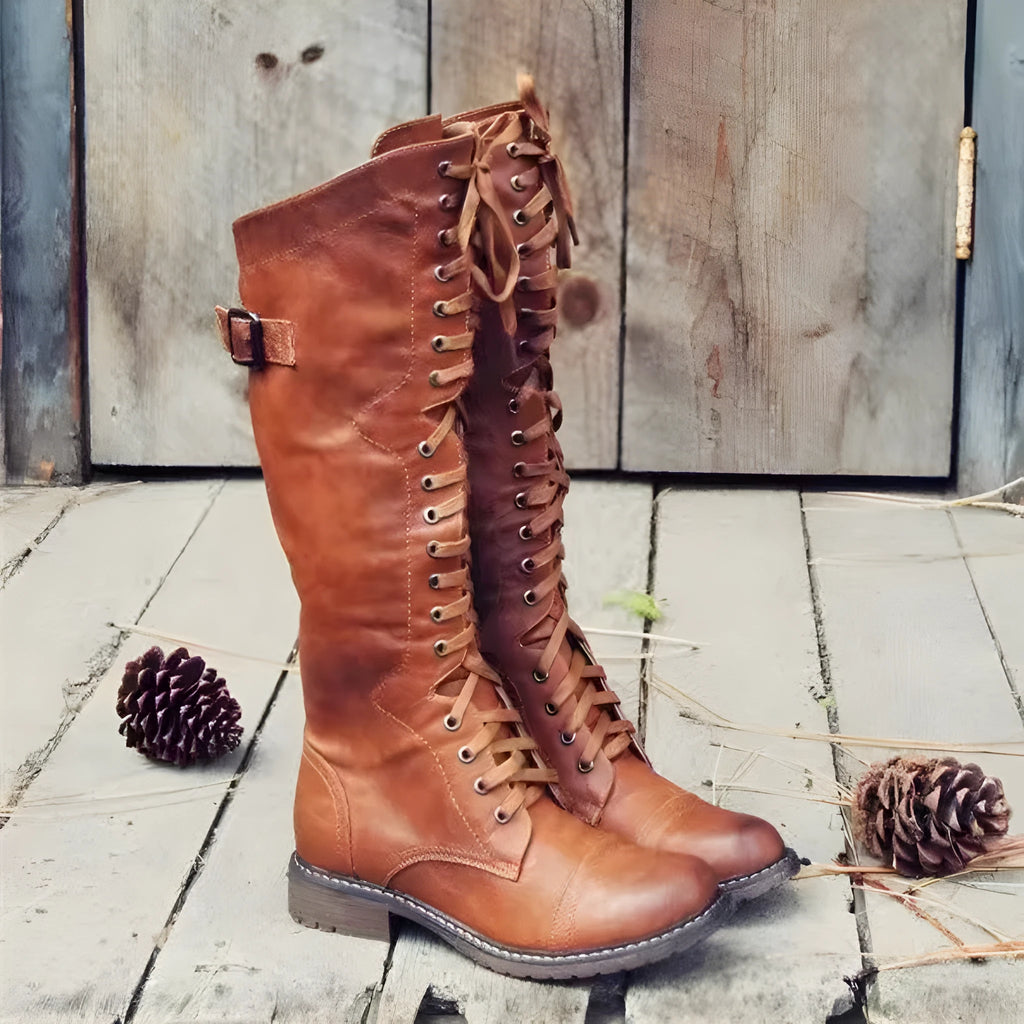 A pair of black chunky heel high leg boots with a round toe on a solid background.