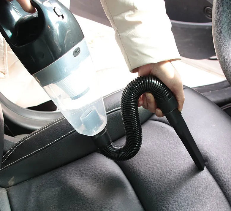 Compact orange handheld car vacuum cleaner with cable next to car seats