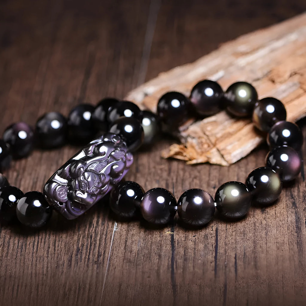 Polished natural crystal Pi Xiu bracelet with geometric ethnic design on a wrist.