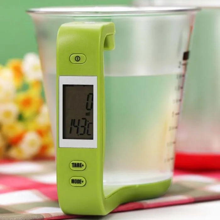 Green electronic digital measuring cup with LCD display on handle showing weight measurement.