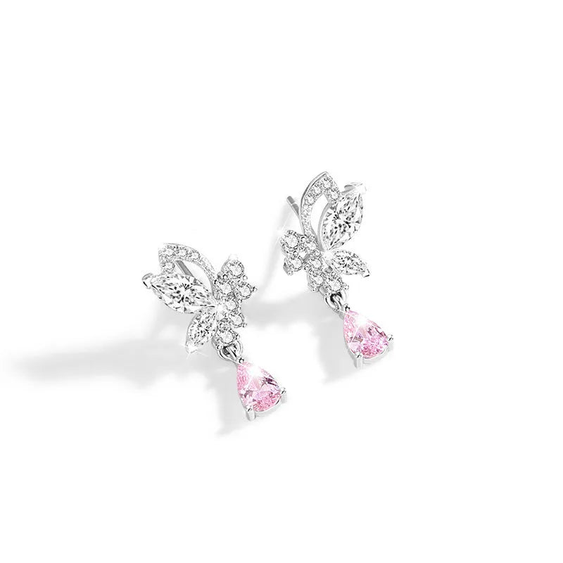 Close-up of a pair of silver butterfly stud earrings on a plain background.