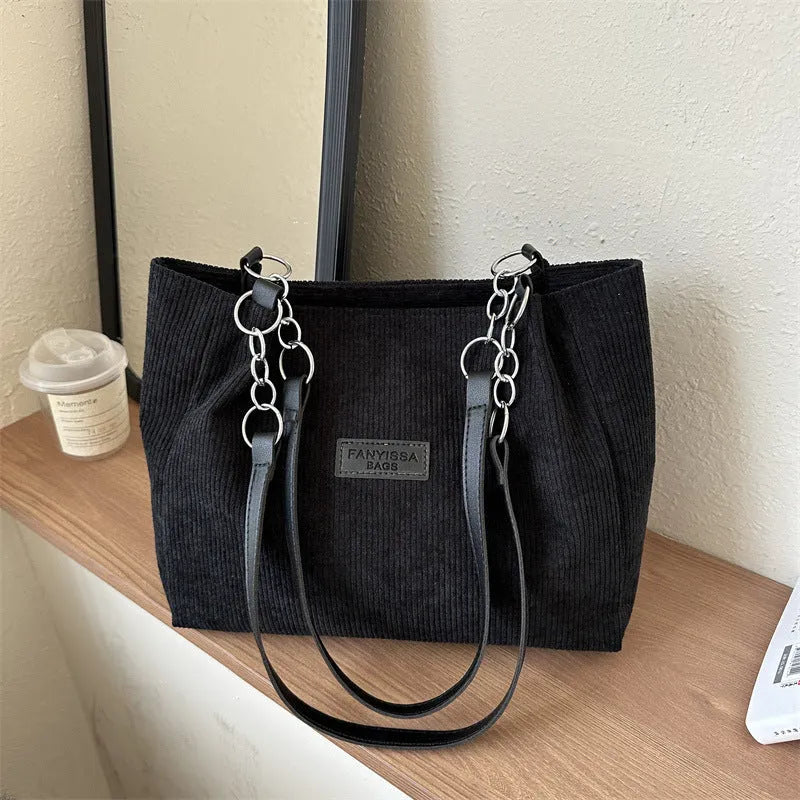 Corduroy one-shoulder tote handbag in a horizontal square shape with a three-dimensional outer pocket.
