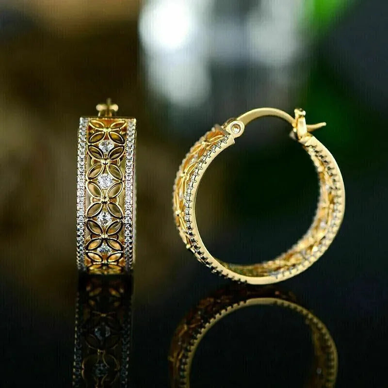 A pair of geometric copper ear clips with horse eye, flower and butterfly motifs in a yellow gold colour.