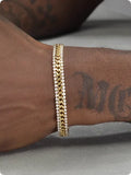 Gold-coloured titanium steel tennis bracelet with inlaid artificial gemstones on a wrist.