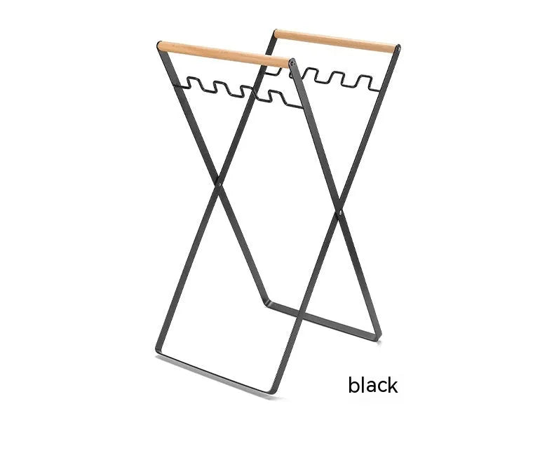 Black foldable iron trash storage hanger with wooden handle holding a bin bag outdoors.