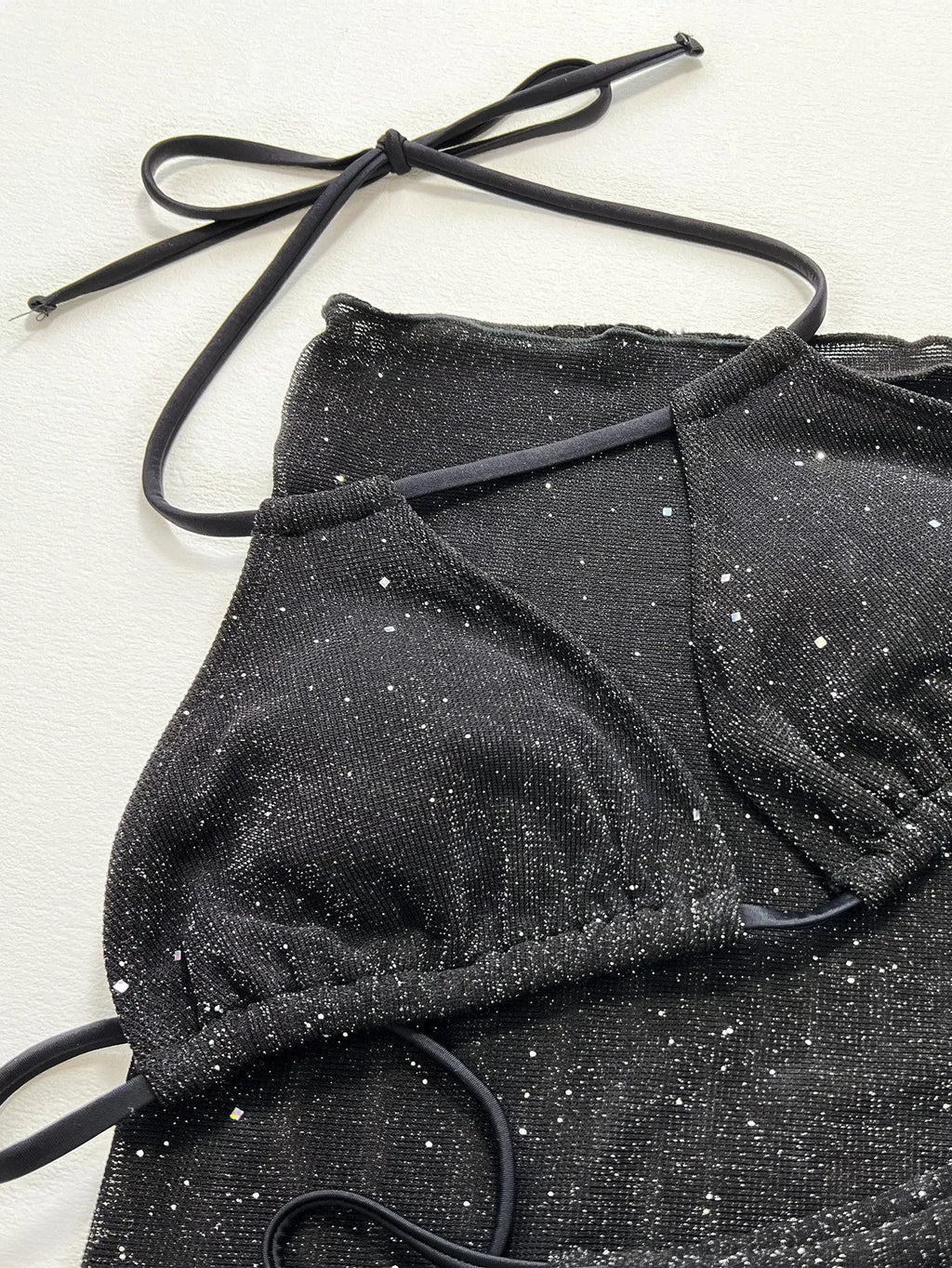 Black three-piece bikini set with bra top and shorts on a mannequin.