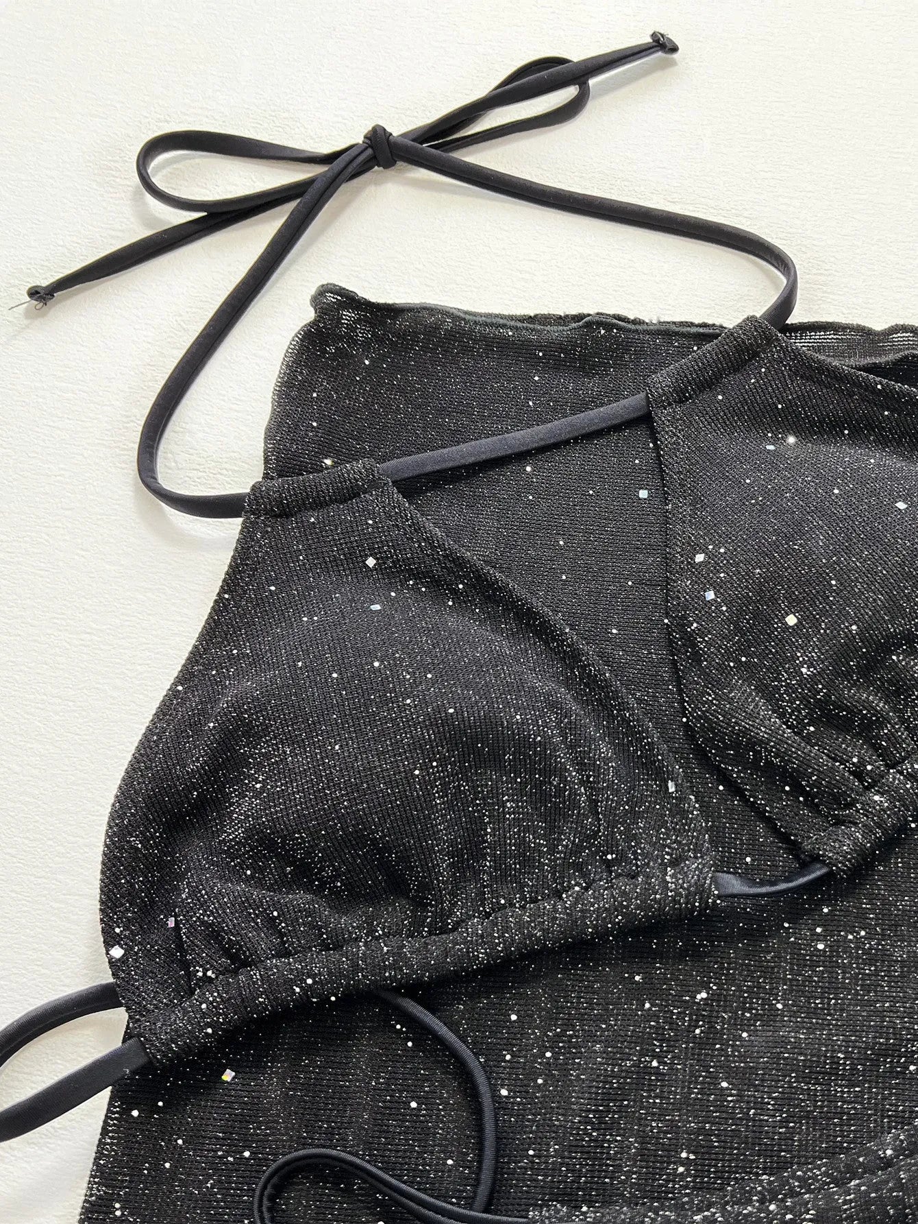 Black three-piece bikini set with bra top and shorts on a mannequin.