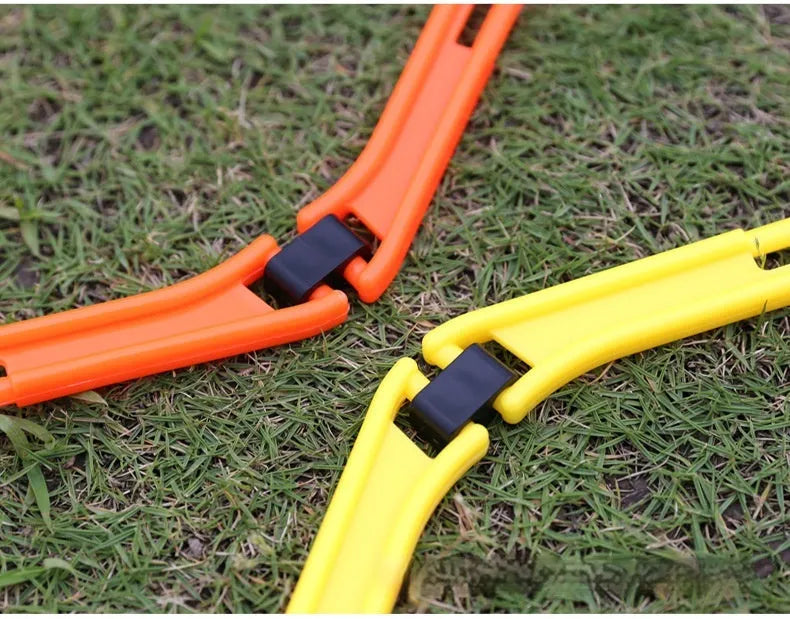 Set of six foldable yellow green and orange hexagon plastic agility training rings laid out on grass