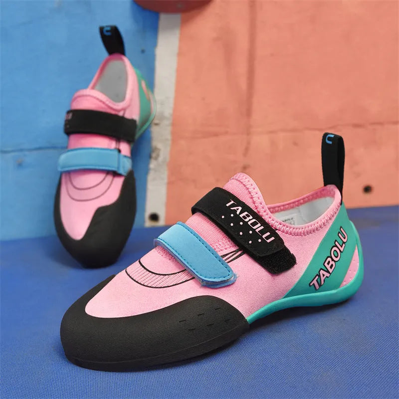 A pair of beginner rock climbing shoes with Velcro straps, shown in a black and red colour scheme.