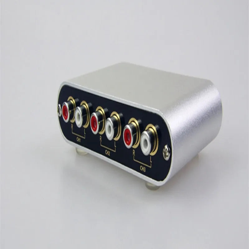 Silver aluminium audio source switch box with remote control for input/output selection.